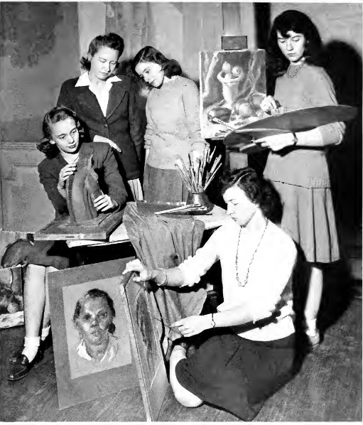 A black and white photo of five woman in the Art Club. One is holding an essal, one is painting while kneeling on the floor, two is working on making a horse head. Two women are in the background looking at the horse head.